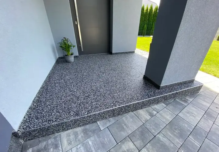 Nowoczesny kamienny dywan koszt 1m2 przy wejściu do domu. Elegancka, szara posadzka z drobnym kamyczkiem.