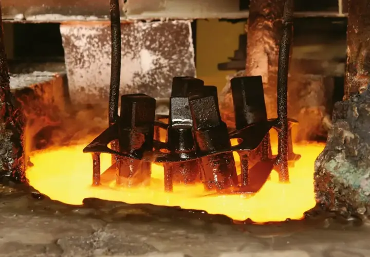 Metalowe elementy zanurzane w rozgrzanym płynie, proces hartowania. Para unosi się wokół.