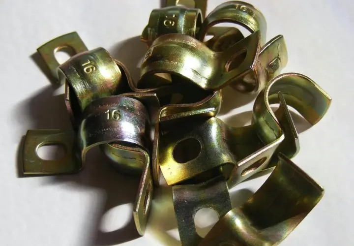 Złote zaciski metalowe, po procesie galwanizacji, z wybitym numerem "16".