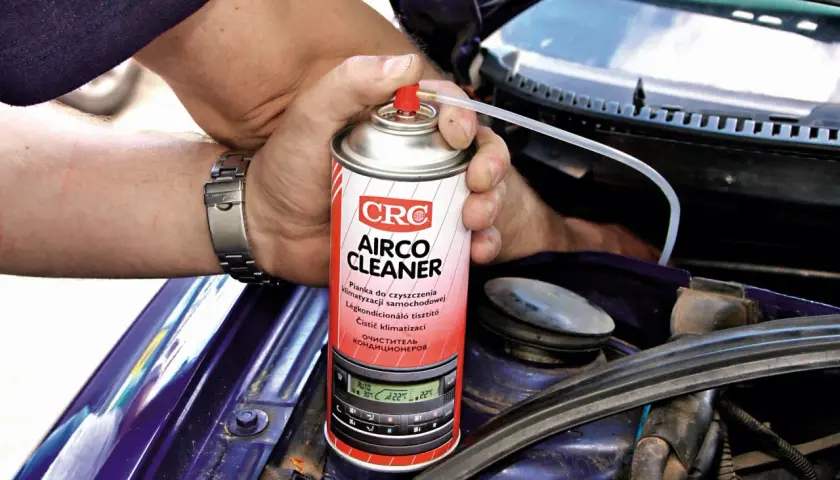 Ręce z zegarkiem trzymają puszkę "Airco Cleaner" do czyszczenia klimatyzacji. Zastanawiasz się, ile kosztuje nabicie klimatyzacji? Ten produkt może pomóc.
